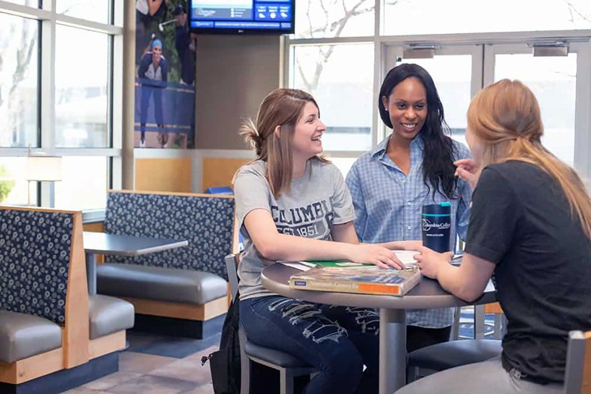 Three students conversing at table